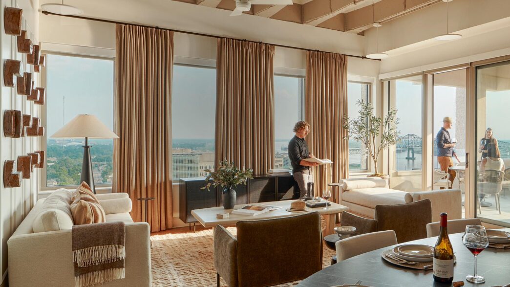 Interior de departamento moderno con ventanales, sala de estar, comedor y balcón. Transformación oficinas a viviendas en LATAM, diseño elegante.