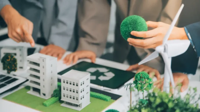 Equipo inmobiliario planea transformación verde: modelos de edificios, turbina eólica y símbolo de reciclaje. Residuos en valor inmobiliario.