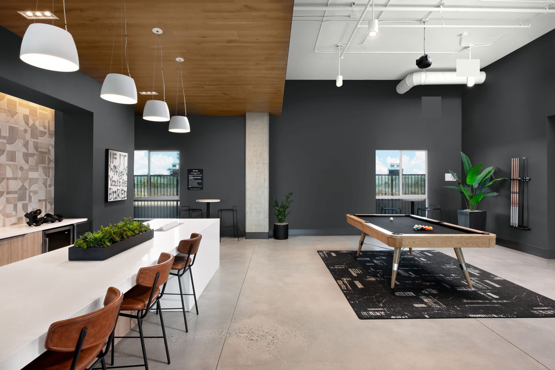 Espacio de recreación con mesa de billar, barra con taburetes y decoración moderna. Transformación digital en real estate y Behr Paint.