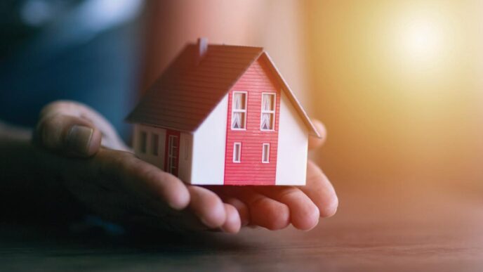 Abstracto: Mano sostiene una casa modelo. Impacto en venta de viviendas en Colombia. Inmobiliare Summits analiza el sector real estate.