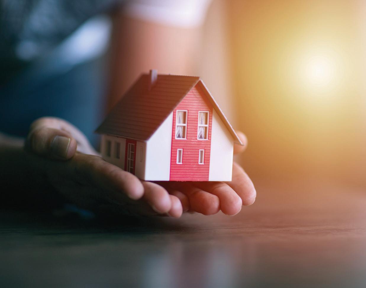 Abstracto: Mano sostiene una casa modelo. Impacto en venta de viviendas en Colombia. Inmobiliare Summits analiza el sector real estate.