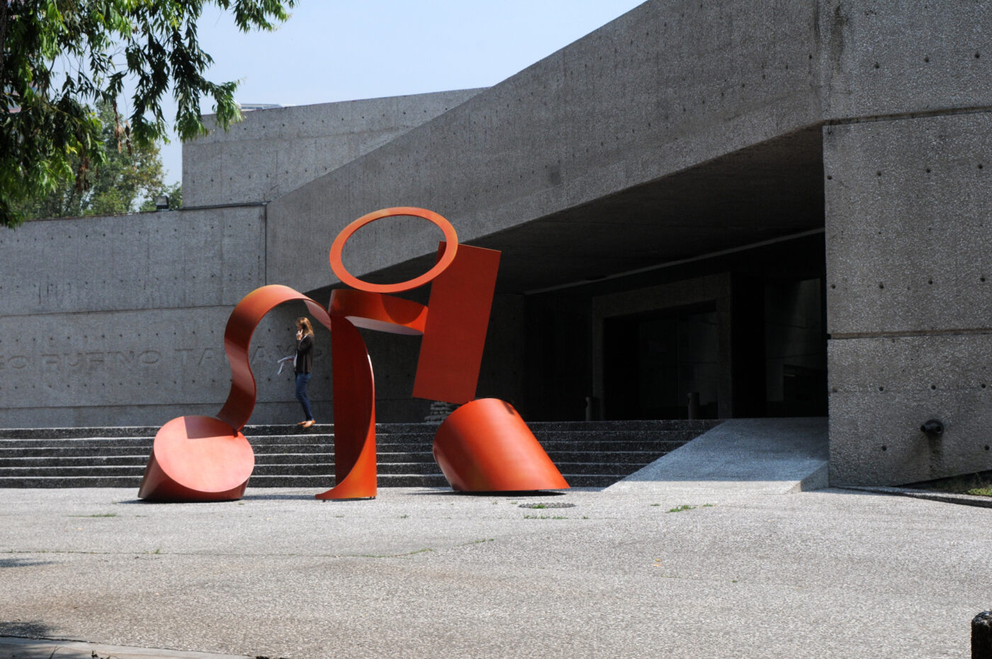 Escultura roja frente al Museo Rufino Tamayo, obra de Teodoro González de León. Mujer subiendo las escaleras. Arquitectura mexicana destacada.