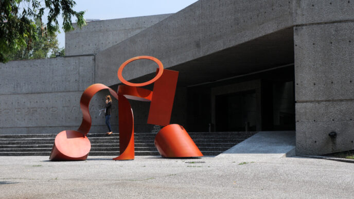 Escultura roja frente al Museo Rufino Tamayo, obra de Teodoro González de León. Mujer subiendo las escaleras. Arquitectura mexicana destacada.