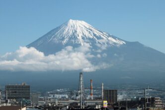 Vista del Monte Fuji, Japón, con nieve en la cima y nubes bajas. Edificios en primer plano. Demolerán edificio que obstruía la vista del Fuji.