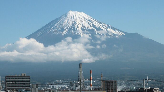 Vista del Monte Fuji, Japón, con nieve en la cima y nubes bajas. Edificios en primer plano. Demolerán edificio que obstruía la vista del Fuji.