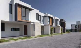 Fila de viviendas modernas en México. Arquitectura minimalista, fachadas blancas y detalles en madera. Costo promedio de vivienda: 1.7 mdp en 2024.