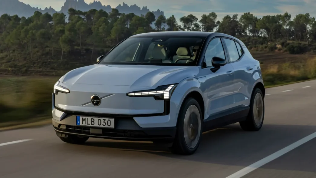 Volvo eléctrico blanco en carretera, destacando innovación en movilidad y real estate. Diseño moderno Volvo con fondo de naturaleza. Volvo y movilidad.