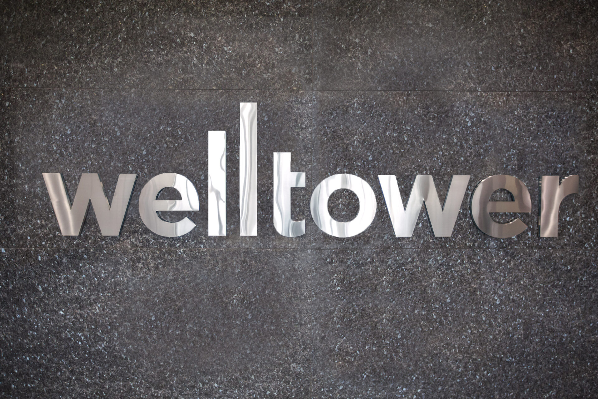 Logotipo de Welltower en pared texturizada. Welltower redefine su portafolio hacia residencias para adultos mayores, un sector en crecimiento.