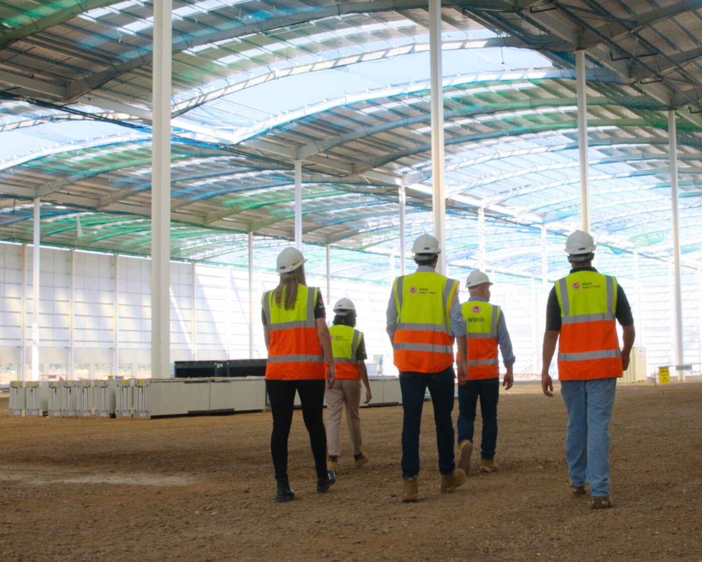 Grupo de ingenieros Winvic inspeccionando construcción Net Carbon Zero. Cascos y chalecos reflejan compromiso Winvic con sostenibilidad y cero emisiones.