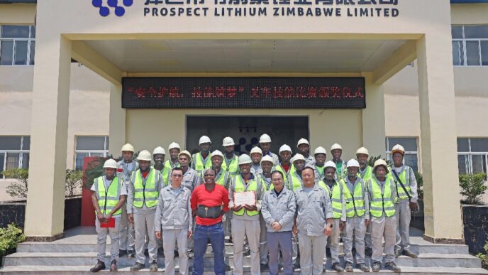 Grupo posando frente a Prospect Lithium Zimbabwe Limited, impulsando energía renovable en planta solar de 70MW. Celebración de éxito y compromiso.