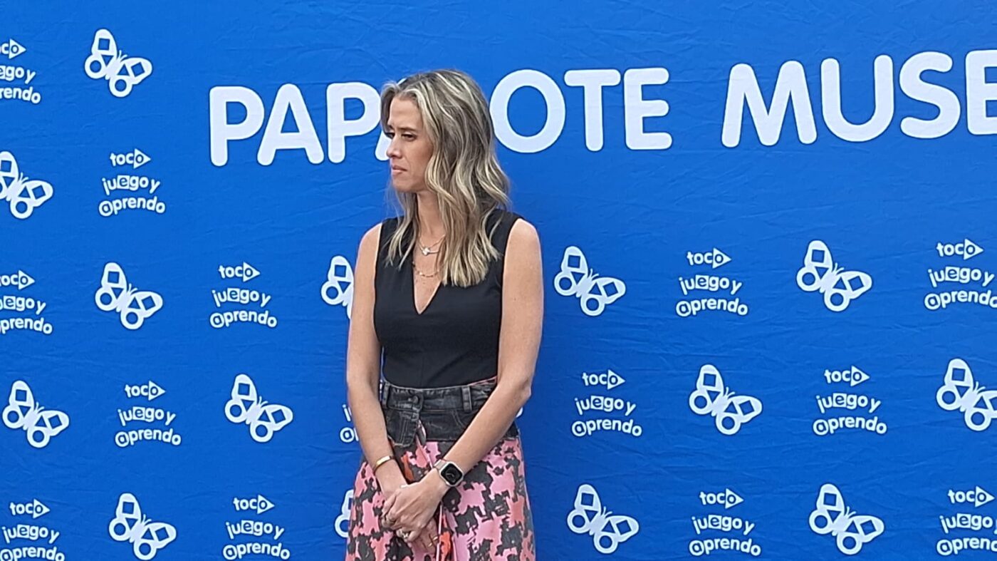 Mujer en el evento "Construye tu ciudad" Papalote Museo del Niño y LEGO. Fondo azul con mariposas y texto "toco juego y aprendo" promoviendo la infancia.