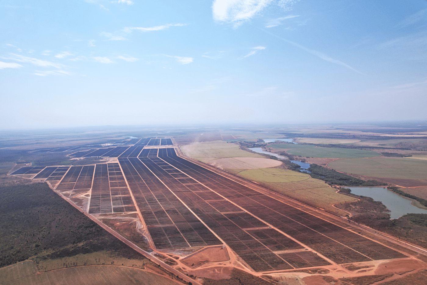 Vista aérea del parque solar de ArcelorMittal en Brasil, mostrando paneles solares extendiéndose hasta el horizonte, reflejando autosuficiencia eléctrica.