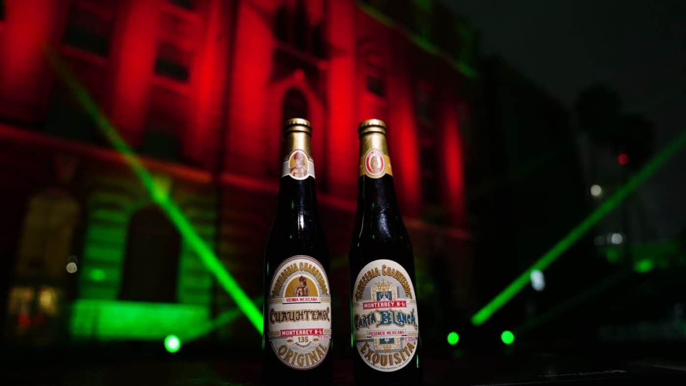 Dos botellas de cerveza Heineken México, celebrando 135 años de tradición cervecera en Monterrey. Cuauhtémoc y Carta Blanca en primer plano.
