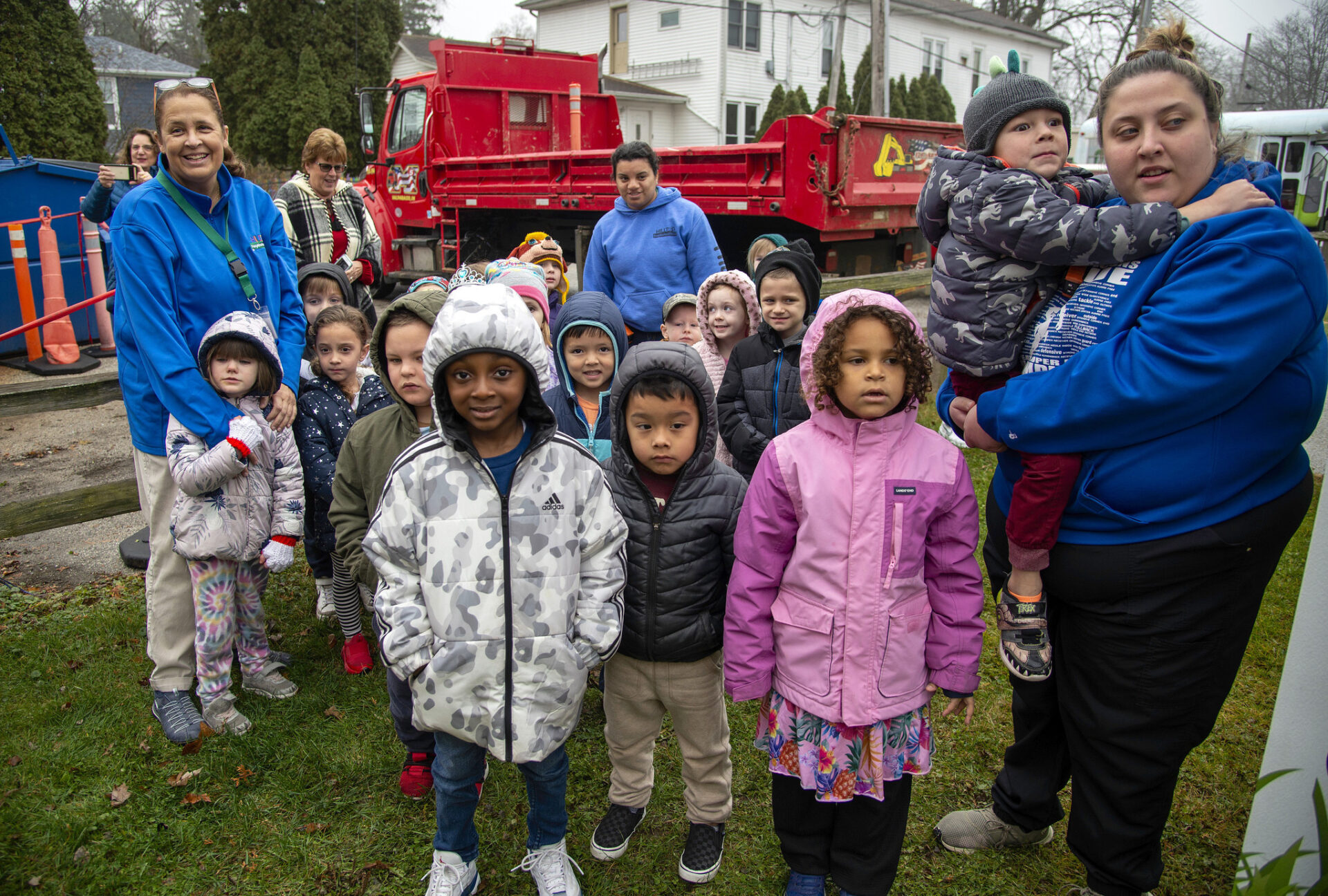 Valparaíso, Indiana: Niños y adultos frente a camión rojo. Hilltop convierte un foco de riesgo en activo comunitario. Proyecto de mejora, unidos.