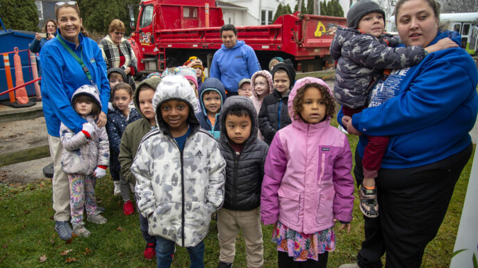 Valparaíso, Indiana: Niños y adultos frente a camión rojo. Hilltop convierte un foco de riesgo en activo comunitario. Proyecto de mejora, unidos.