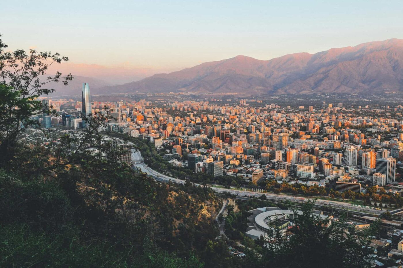Vista de la ciudad de Santiago al atardecer con edificios, montañas y texto IA shapes permisos en Chile.