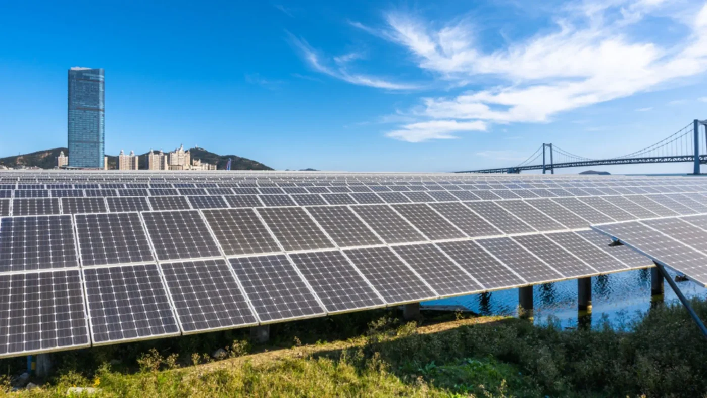 Paneles solares en Pradera Larga, proyecto sustentable de limes en Chile. Vista de la planta con puente y edificio al fondo. Energía renovable.