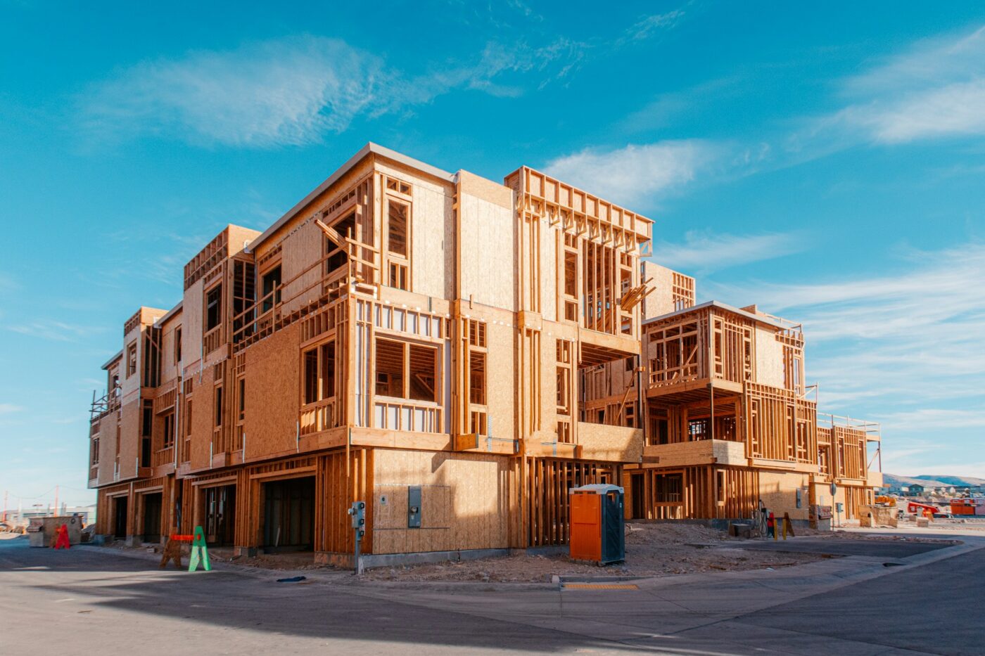 Edificio de tres pisos Sekisui House en obra, estructura de madera visible y cielo azul al fondo.