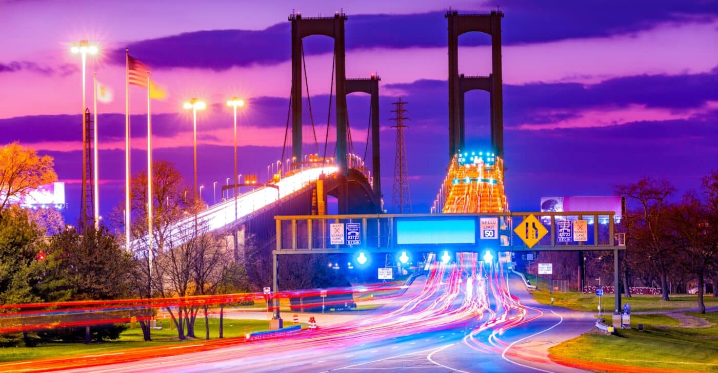 Puente colgante con luces encendidas, tráfico en movimiento y barreras acústicas sobre autopista en Estados Unidos.