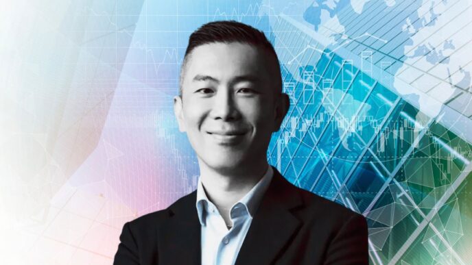 Persona con traje sonríe frente a mapas digitales y gráficos financieros, referencia al pronóstico CBRE 2026.