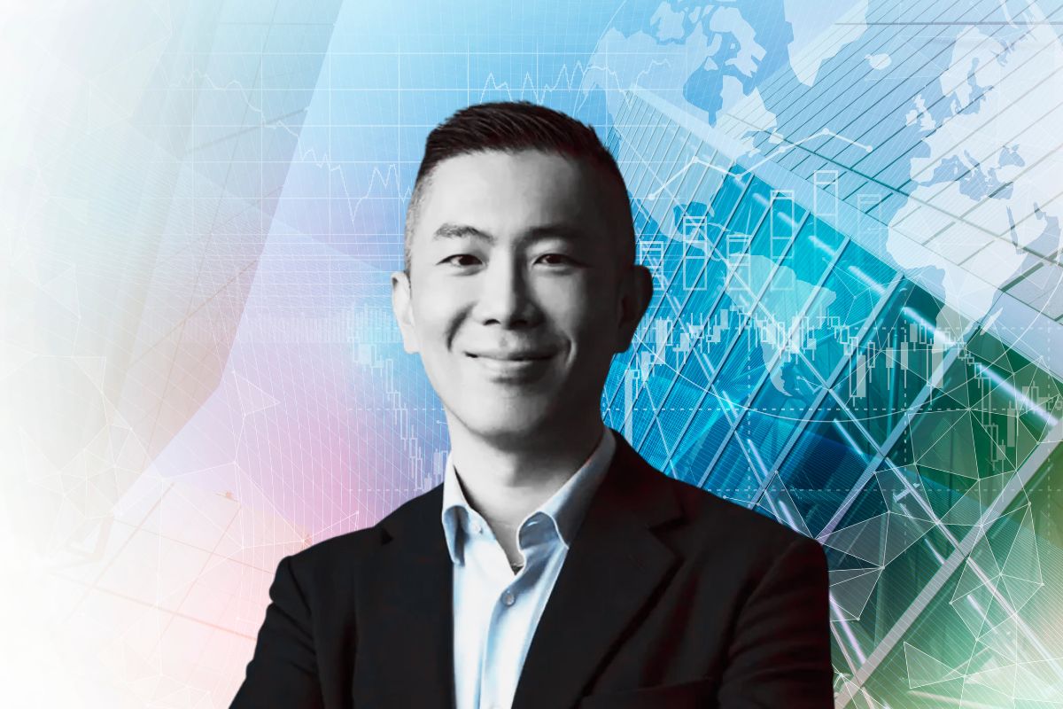 Persona con traje sonríe frente a mapas digitales y gráficos financieros, referencia al pronóstico CBRE 2026.