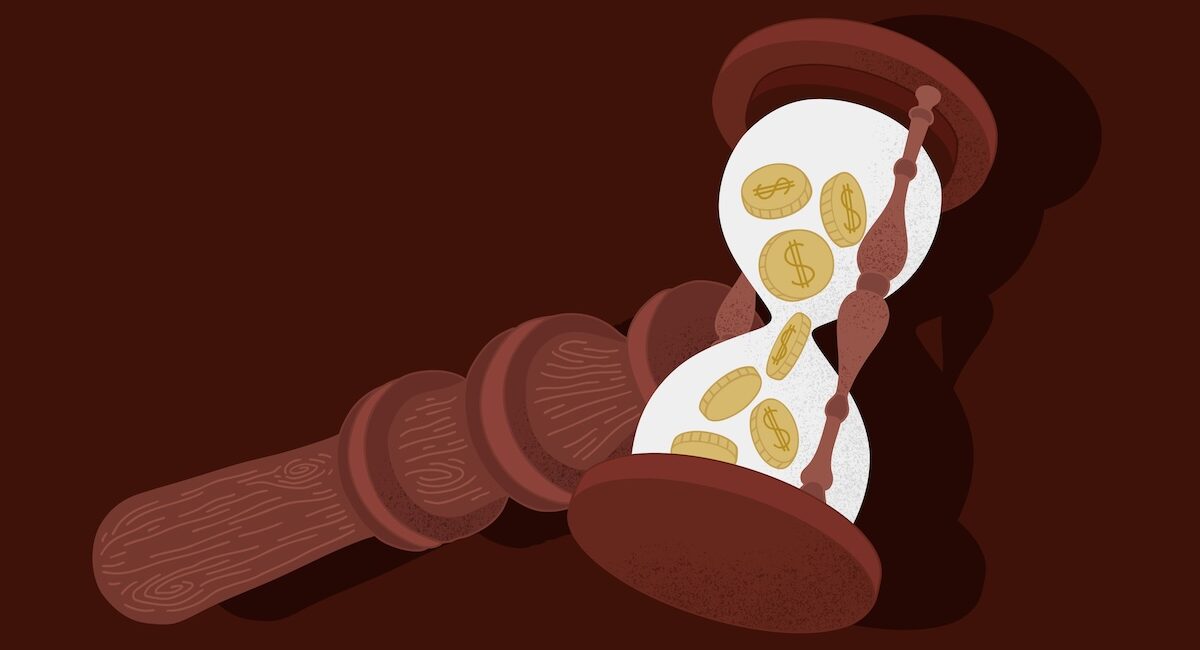 Persona coloca un mazo de madera junto a un reloj de arena con monedas visibles.