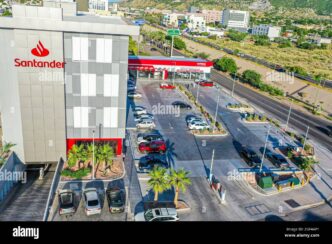 Vista aérea de Santander Distrito Querétaro con estacionamiento, autos y personas junto a avenida concurrida.
