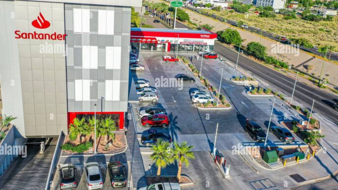 Vista aérea de Santander Distrito Querétaro con estacionamiento, autos y personas junto a avenida concurrida.