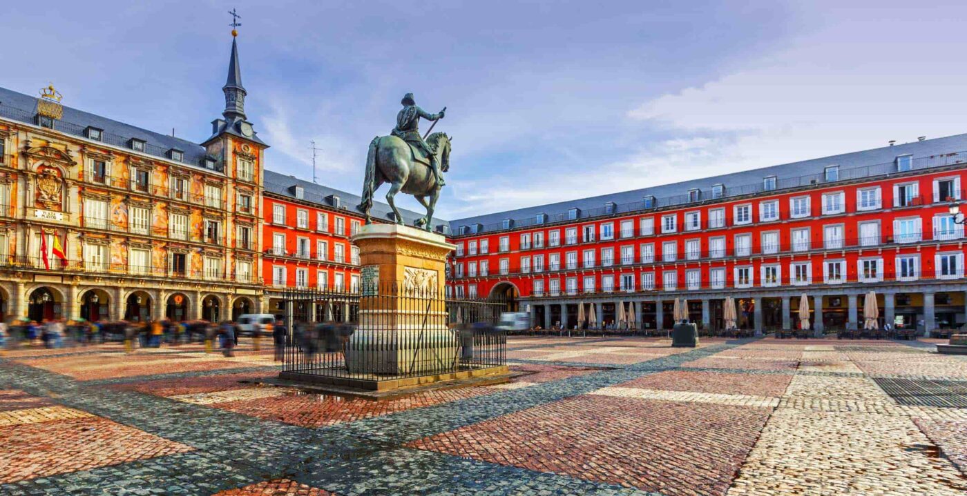 Estatua de persona montada a caballo en Plaza Mayor, Madrid, rodeada de edificios rojos.