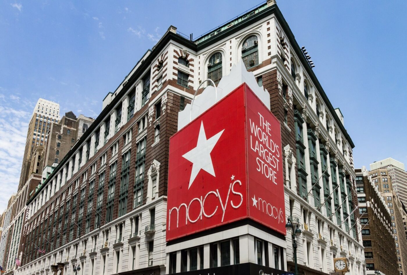 Persona afuera de tienda Macy's en centro comercial, letrero rojo visible en esquina del edificio.