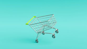 Carrito de metal con asa amarilla vacío sobre fondo turquesa con texto tendencias de retail innovation.