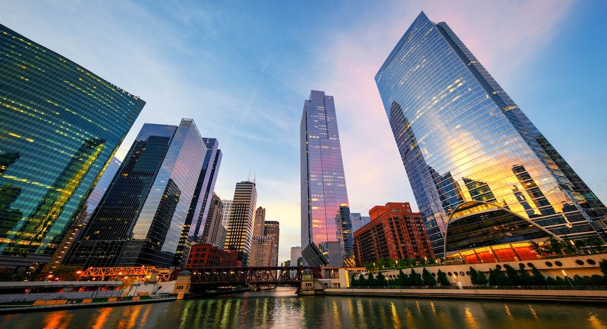 Rascacielos de vidrio reflejan la luz del atardecer junto a un río y el logo de Barnes & Noble en Chicago.