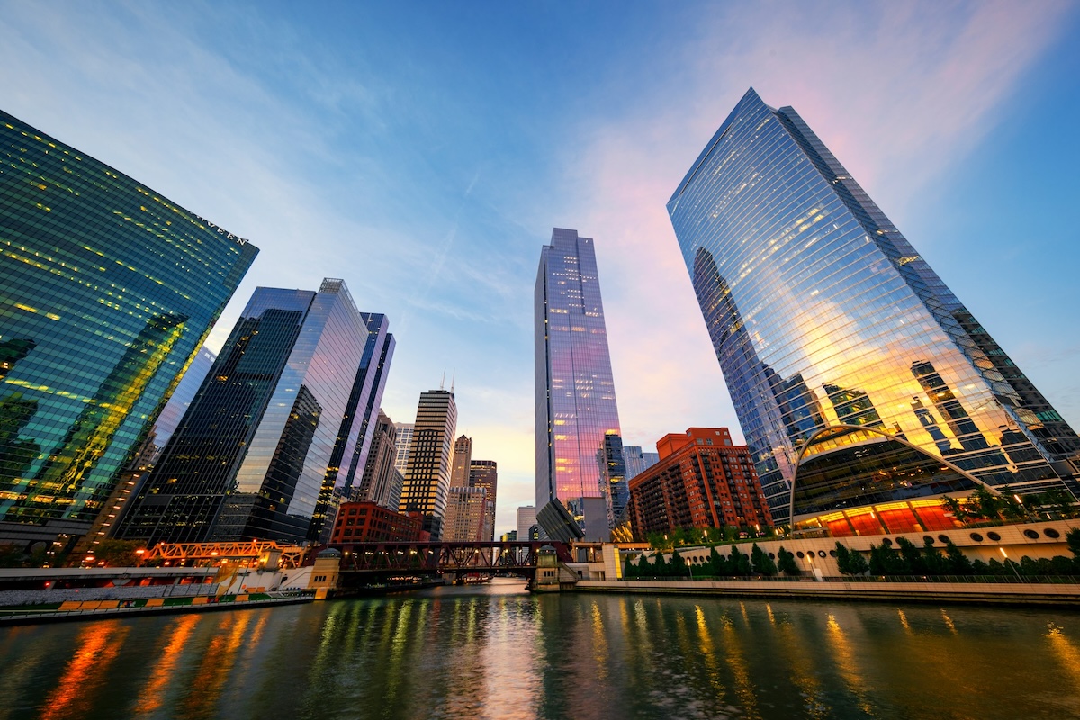 Rascacielos de vidrio reflejan la luz del atardecer junto a un río y el logo de Barnes & Noble en Chicago.