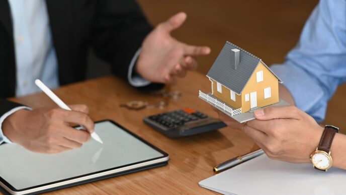 Dos personas conversan en un mercado, una sostiene maqueta de casa y otra escribe en tablet.