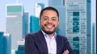 Persona de traje con brazos cruzados frente a oficinas modernas en el evento IMEI BOMA 2027.