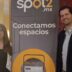 Dos personas junto a lona de Spot2.mx con texto Conectamos espacios en oficinas corporativas Santa Fe.