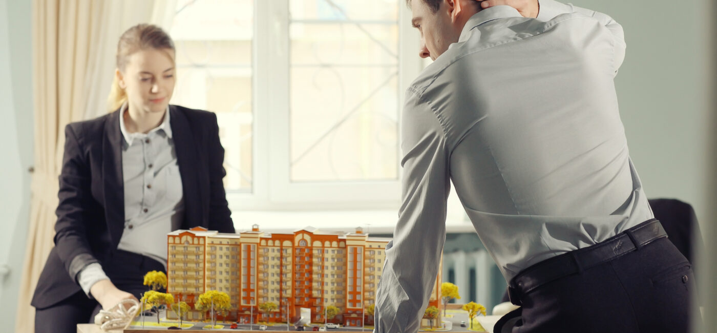 Dos personas con ropa formal observan una maqueta inmobiliaria en México.