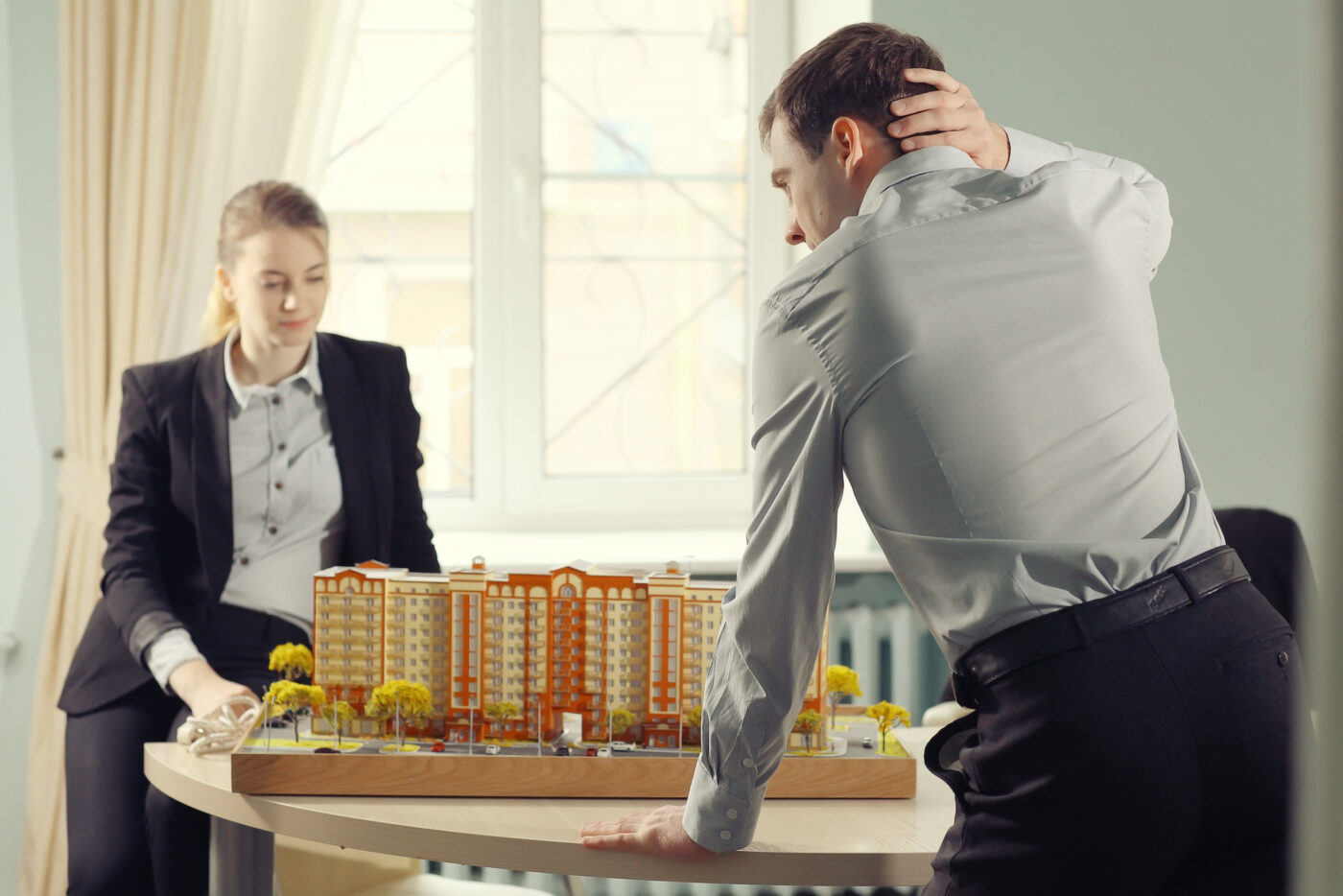 Dos personas con ropa formal observan una maqueta inmobiliaria en México.